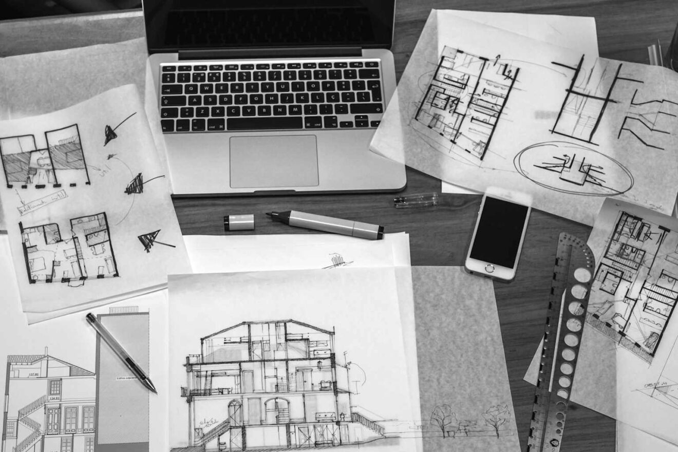 An architect's desk with drawings, a laptop and pencils